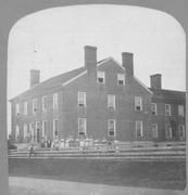 SA0416 - Photo of a large brick building and people standing along a fence. Associated with the West Family. Identified on the back.